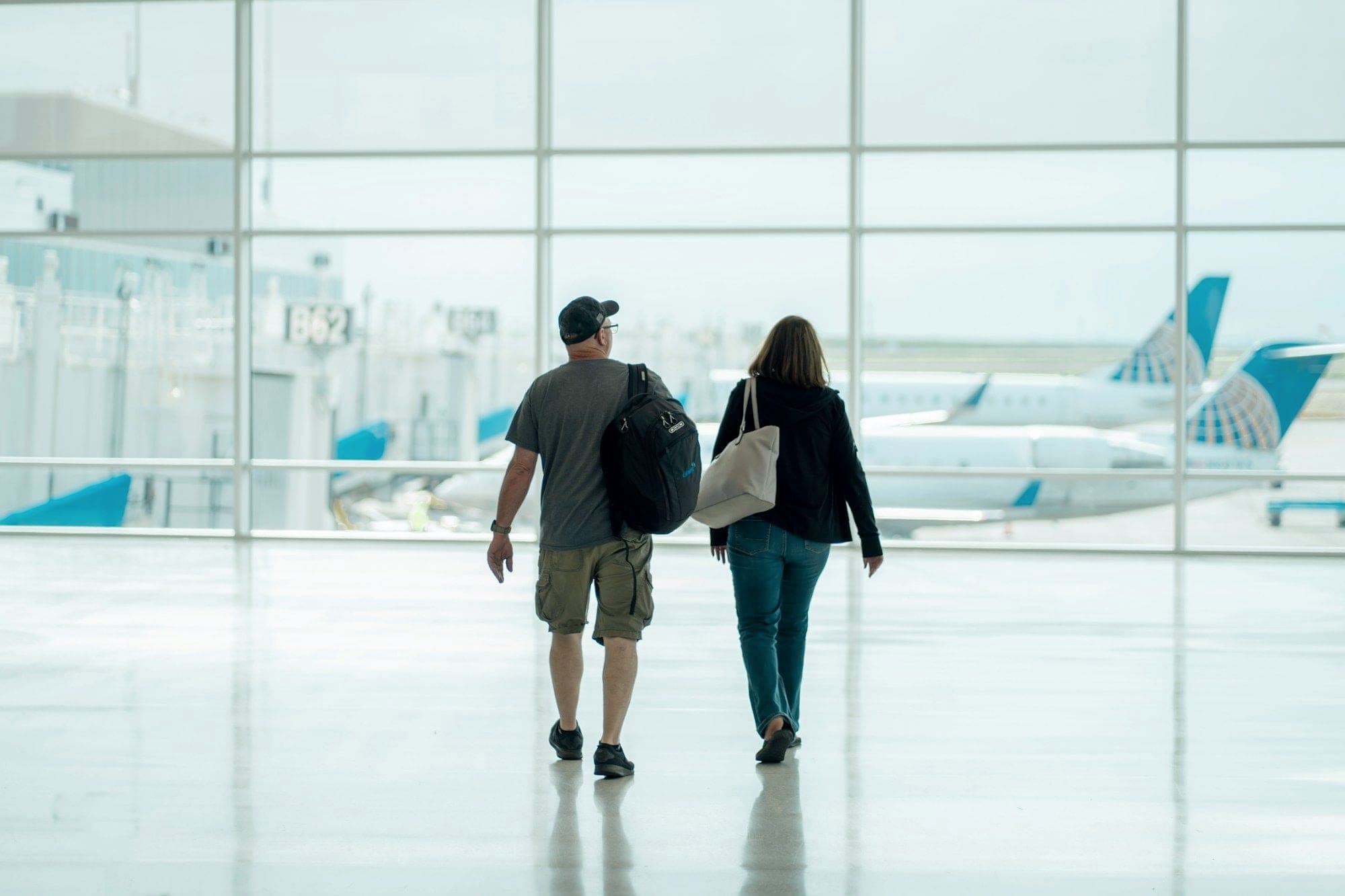 Una pareja camina con sus mochilas por la terminal de un aeropuerto hacia su vuelo